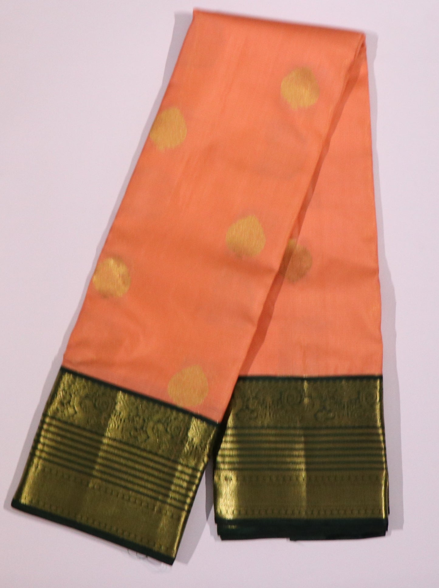Kanchi Silks-Body-Warm Peach–Salmon Tone-Round gold zari buttas-Border-zari border-Deep olive-black undertone.
